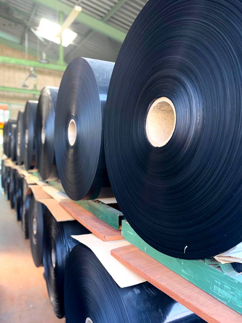 Bobines mères de film noir extrudé, stockées dans l'atelier